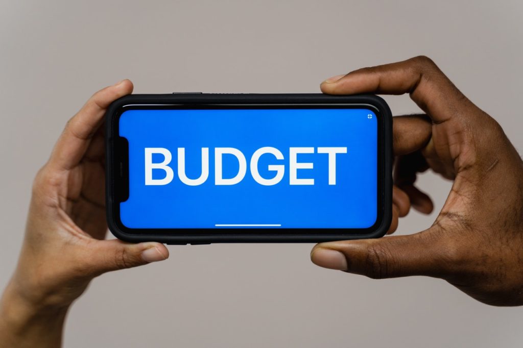 Hands holding a smartphone with the word BUDGET