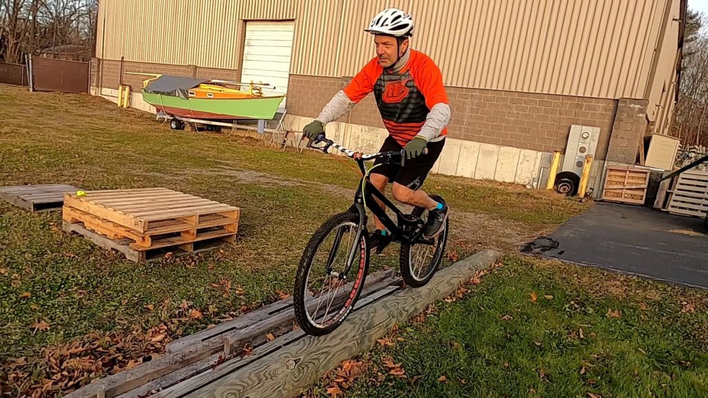 Tony rides his trials bike down a skinny log